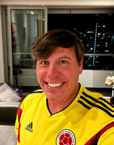 This is a selfie of Content Writing & Copywriting's Seth Mason wearing a Colombian national soccer jersey. You can see the Medellín skyline in the background of his home office.